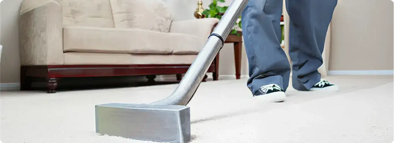 Carpet cleaning technician using a hot-water extraction wand on a light-colored carpet in a living room, Erie, PA.